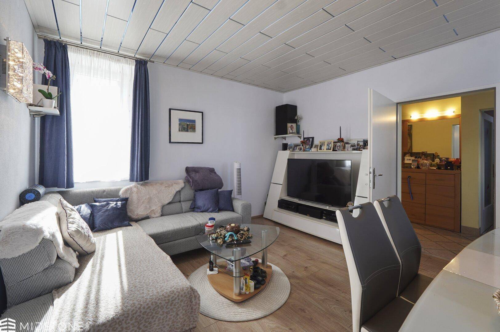 Heller Wohn- und Essbereich mit Holzboden, Sofa und Esstisch.