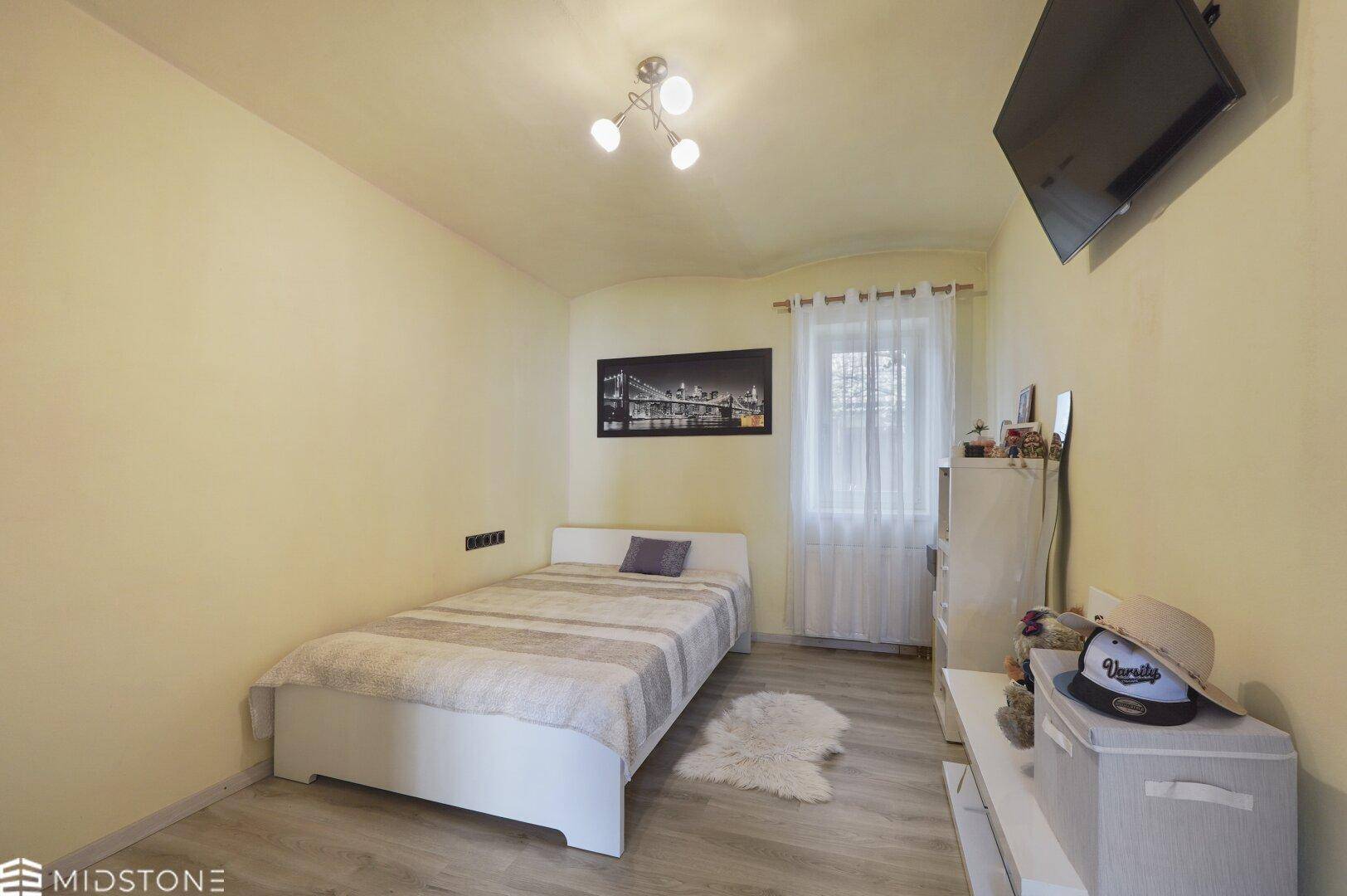 Kleines Schlafzimmer mit Einzelbett, Holzboden und einem Fenster.