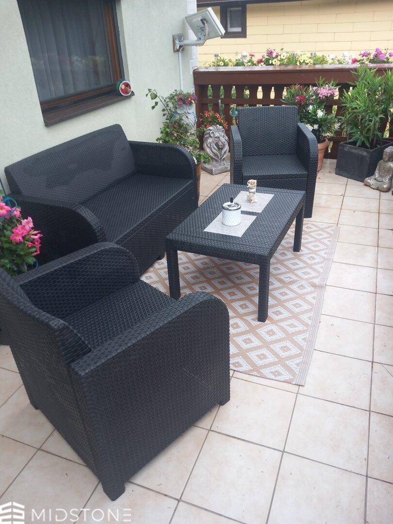 Gemütliche Terrasse mit Rattanmöbeln und Blumen, ideal zum Entspannen im Freien.