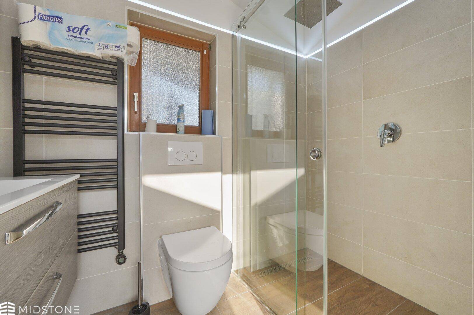 Modernes Badezimmer mit begehbarer Dusche, WC und beheiztem Handtuchhalter.