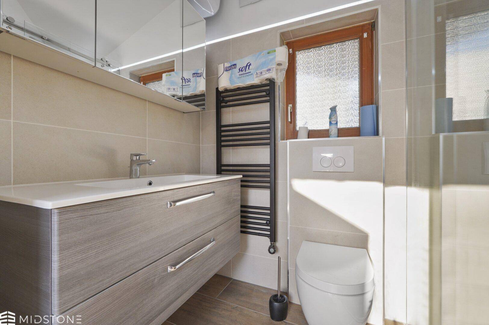 Helles Badezimmer mit modernem Waschtisch, Spiegel und begehbarer Dusche.
