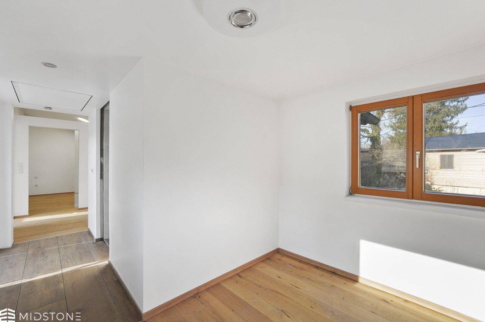 Heller Raum mit Holzboden und Fenster, ideal als Schlaf- oder Wohnbereich.