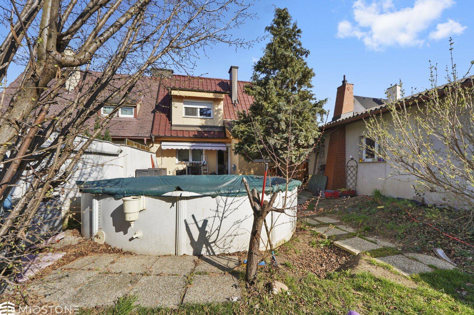Hinterhof mit oberirdischem Pool, Rasenfläche und Terrasse am Haus.