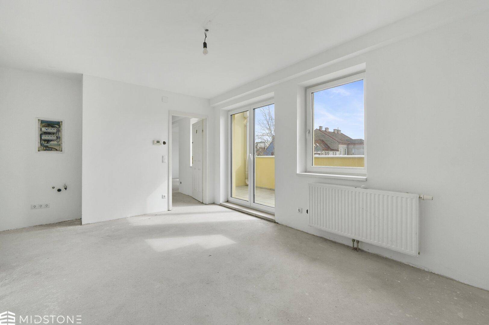 Heller, unmöblierter Wohnbereich mit Zugang zum Balkon und Blick auf die Umgebung.