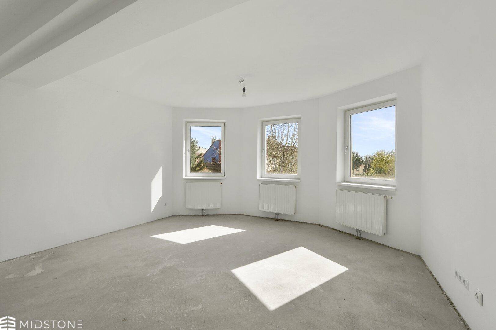 Heller, leerer Raum mit drei Fenstern und Betonboden, bietet viel Tageslicht und Gestaltungspotenzial.