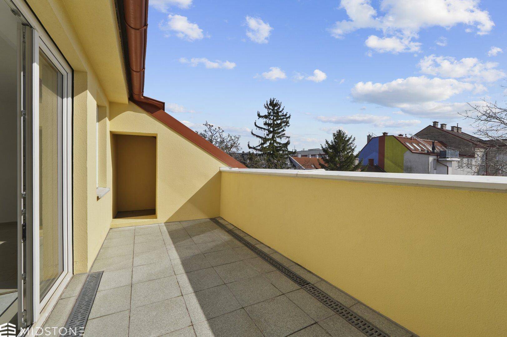 Geräumiger Balkon mit Fliesenboden und gelben Wänden, bietet einen schönen Blick auf die Umgebung.