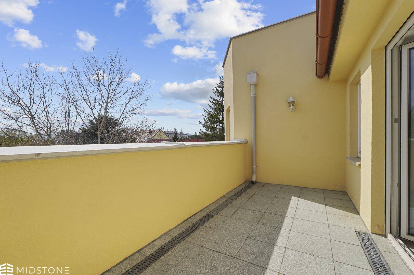 Heller Balkon mit Fliesenboden und gelben Wänden, ideal zum Entspannen im Freien.
