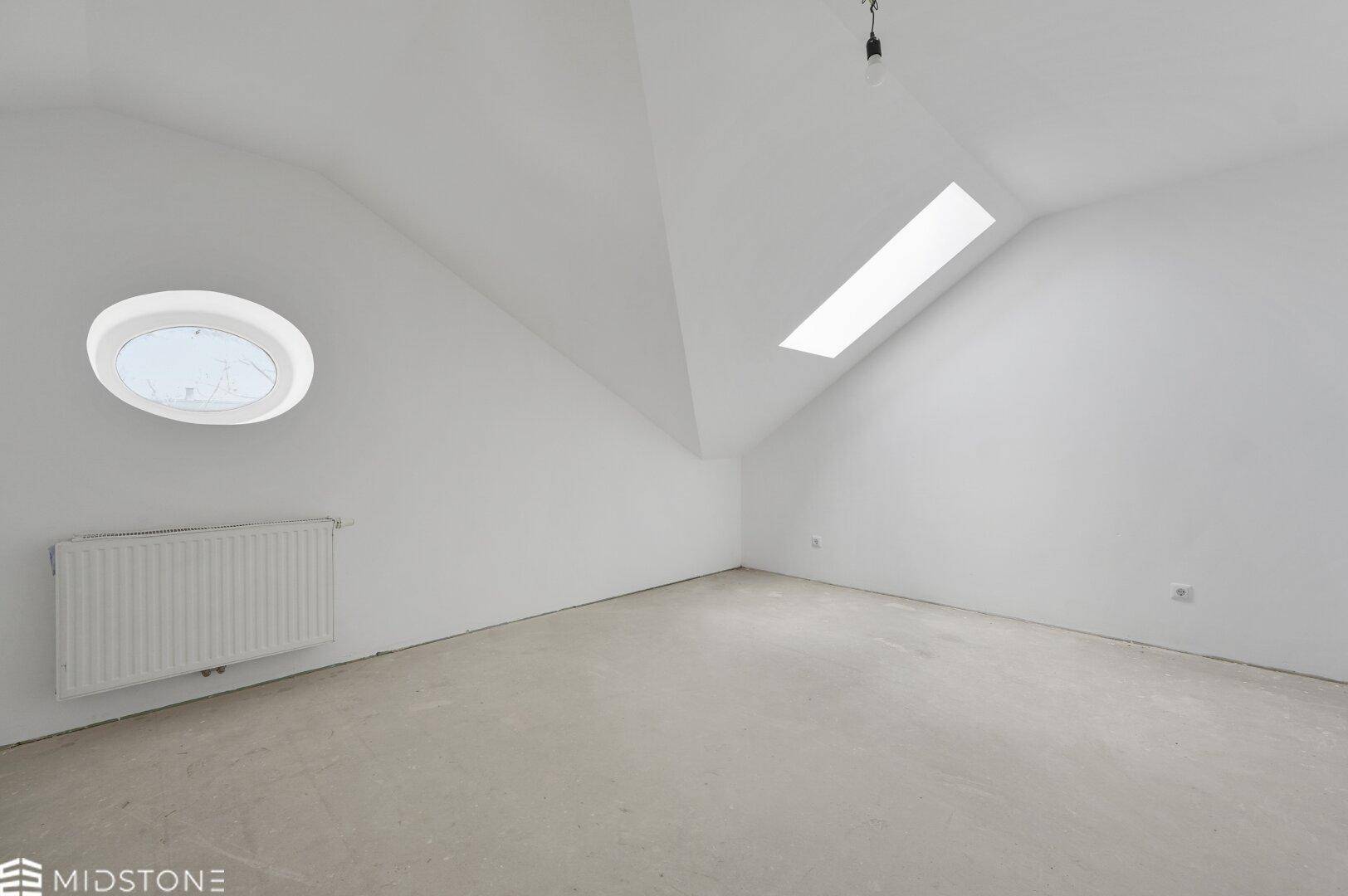 Leeres Dachgeschosszimmer mit schrägen Wänden, Dachfenstern und Betonboden, bereit für den Ausbau.