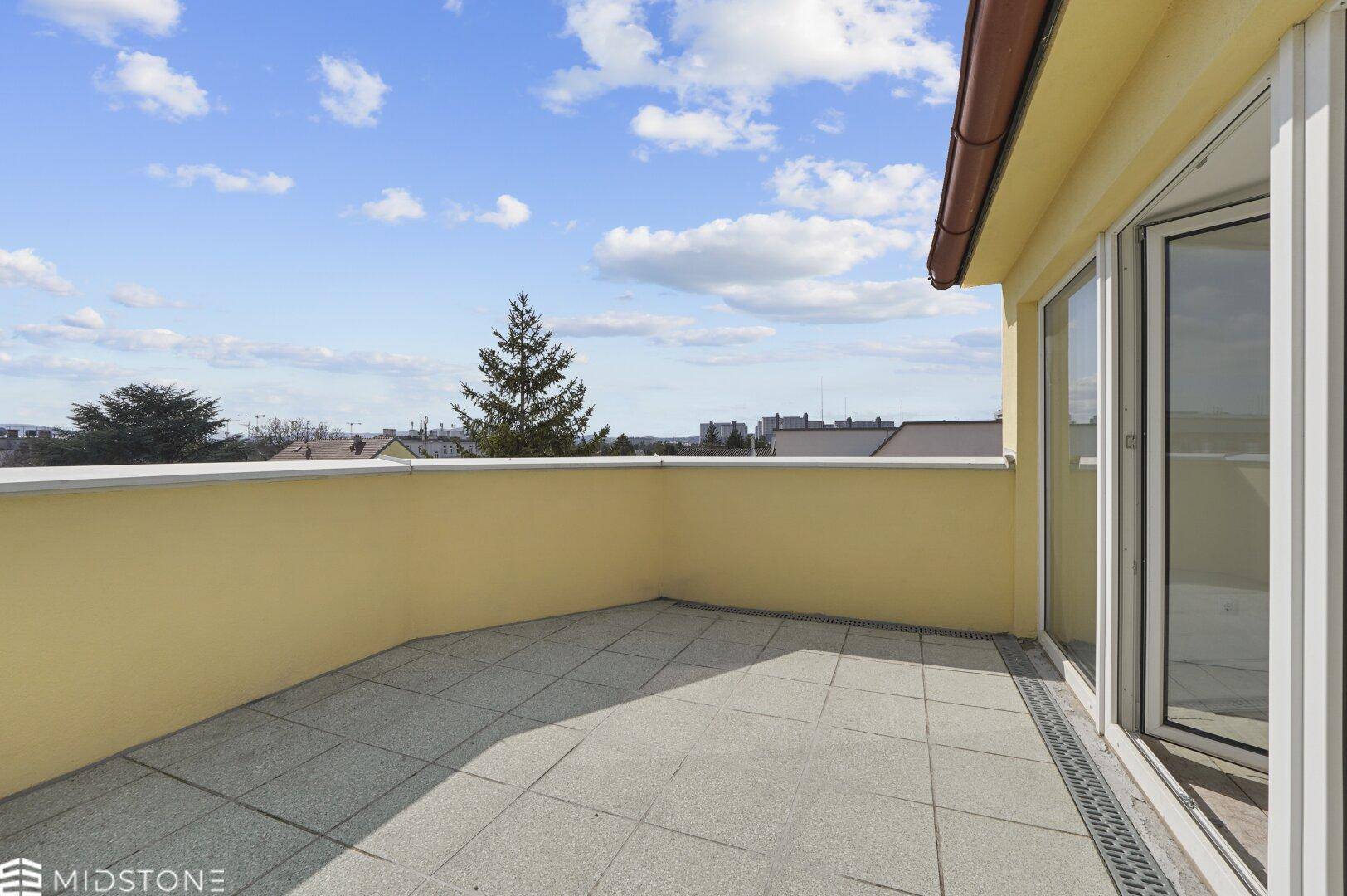 Großer Balkon mit Fliesenboden und gelben Wänden, bietet viel Platz und eine weite Aussicht.