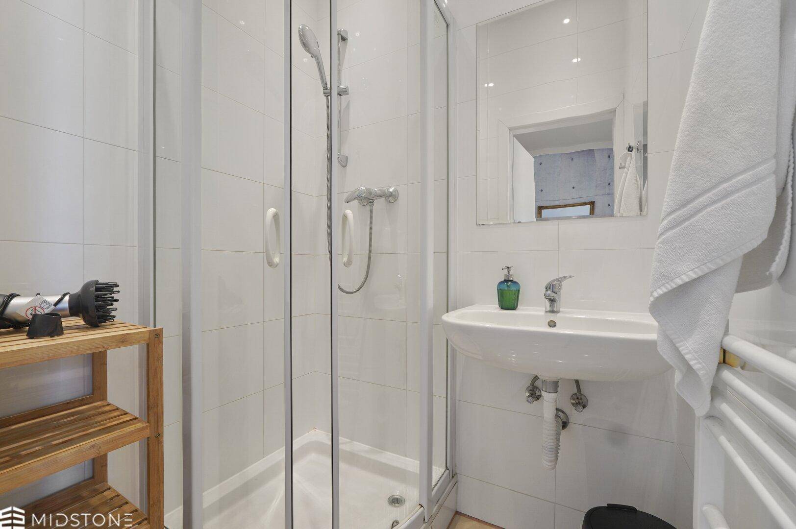 Modernes Badezimmer mit Duschkabine, Waschbecken und weiß gefliesten Wänden.