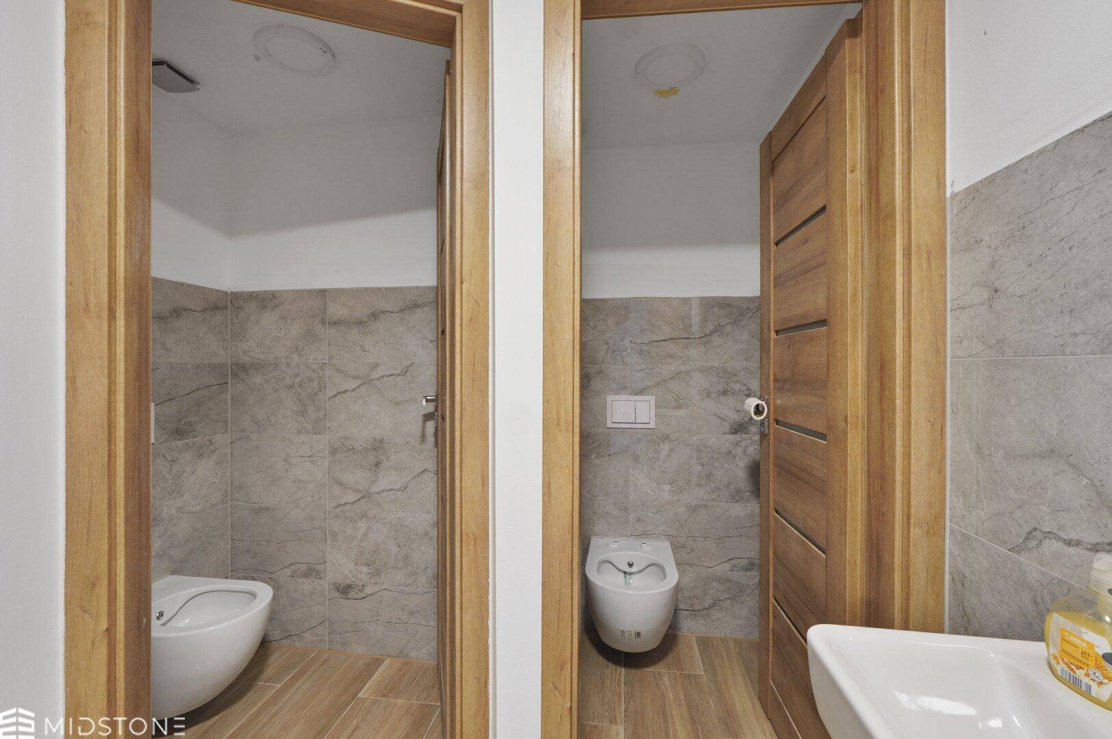 Zwei separate Toilettenräume mit modernen WCs und Fliesen, sauber und funktional.