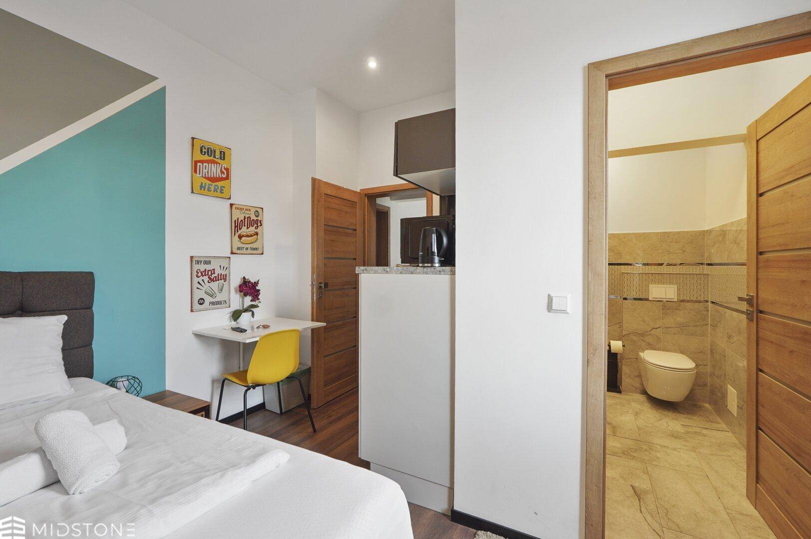 Kompaktes Studio-Apartment mit Küchenzeile und Schlafbereich, Zugang zum Bad, praktisch eingerichtet.