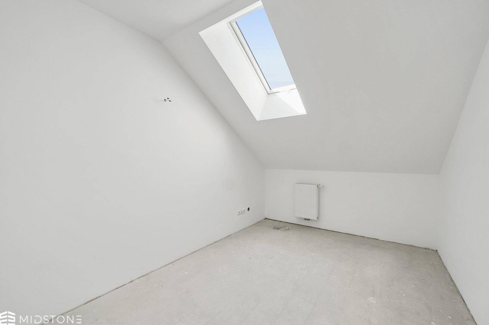 Kleines Dachzimmer mit einem Dachfenster und Betonboden, ideal als Kinderzimmer.