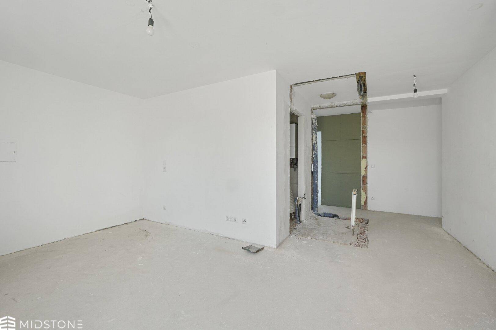 Unfertiger Innenraum mit freigelegten Wänden und Betonboden, bereit für den Ausbau.