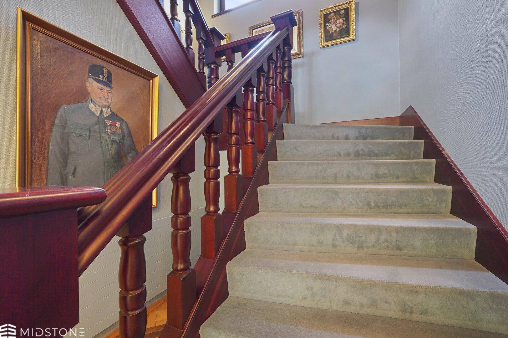 Elegante Holztreppe mit Teppichstufen und einem klassischen Gemälde an der Wand.