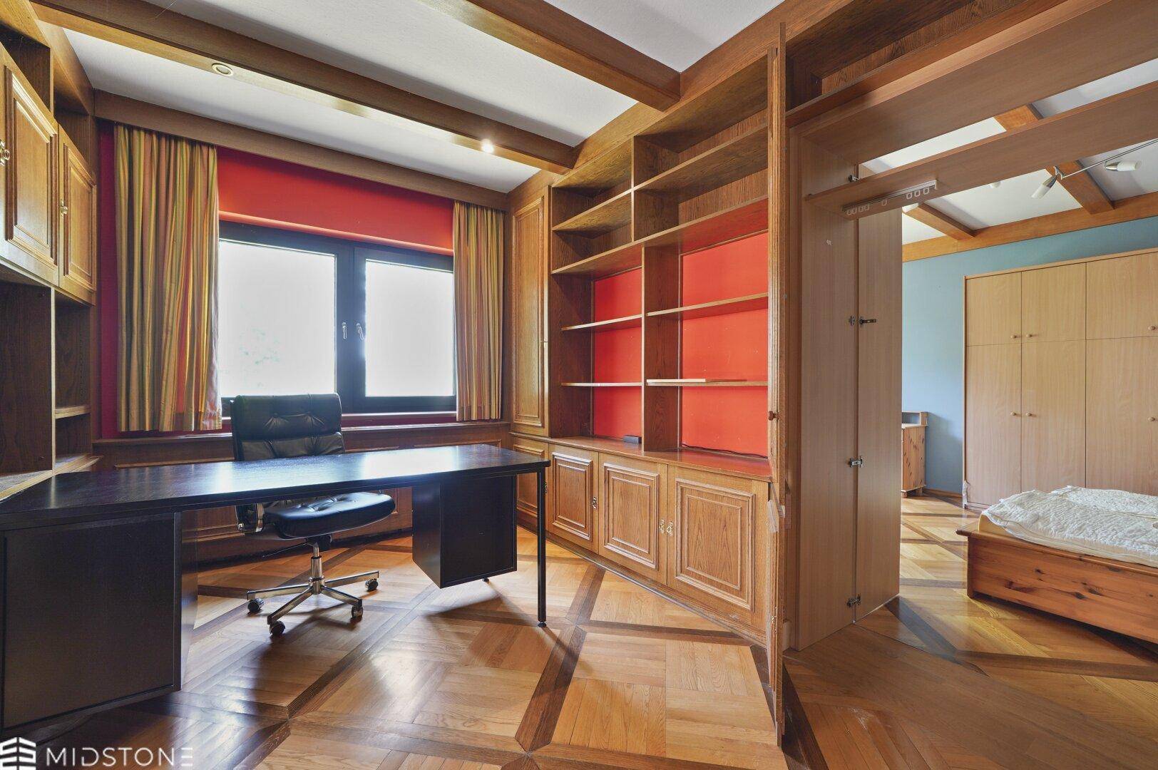 Arbeitszimmer mit maßgefertigten Holzregalen, Schreibtisch und Blick ins Grüne.