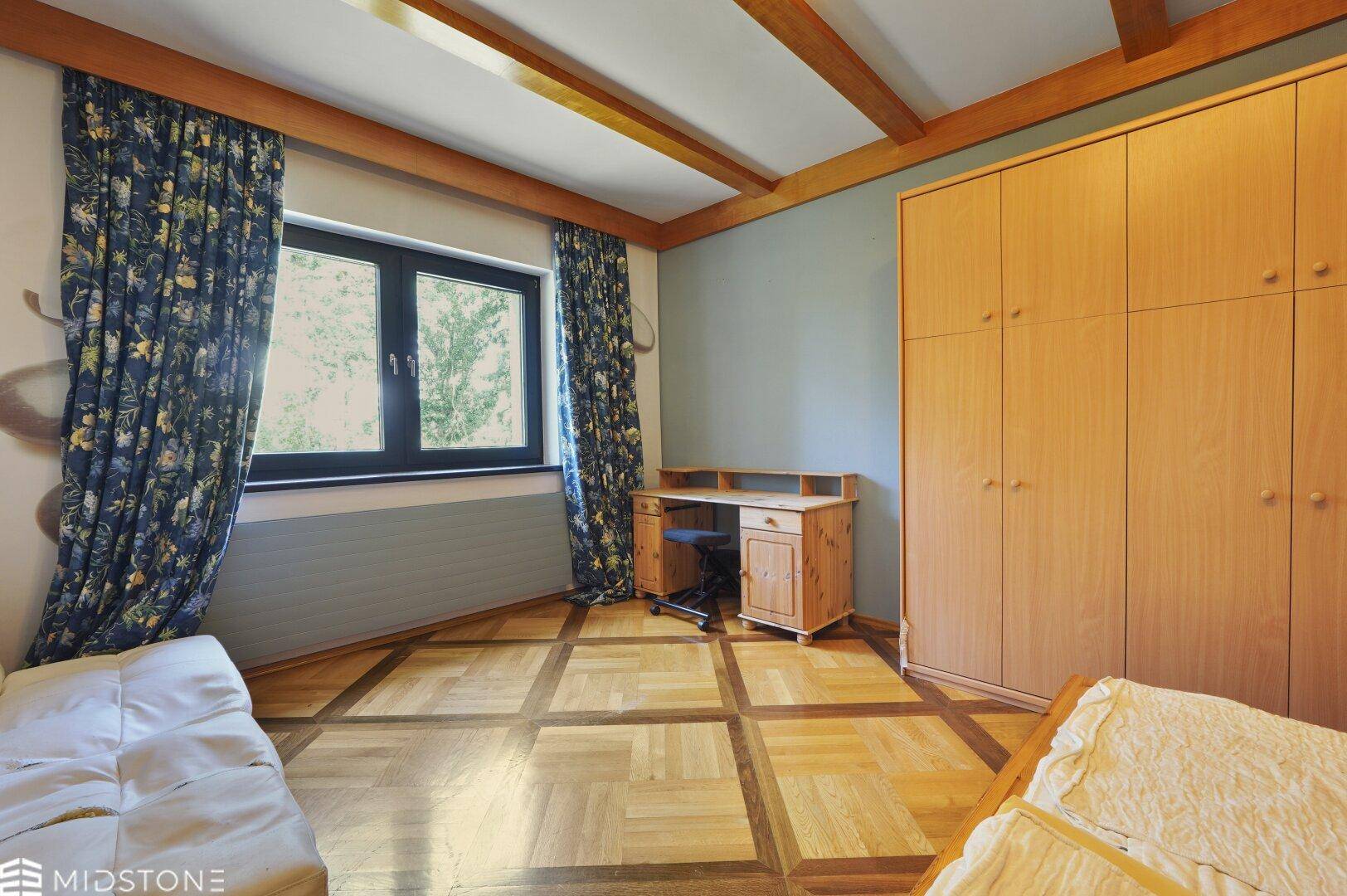 Gemütliches Schlafzimmer mit Holzboden, Einbauschrank und Fenster mit Blick ins Grüne.