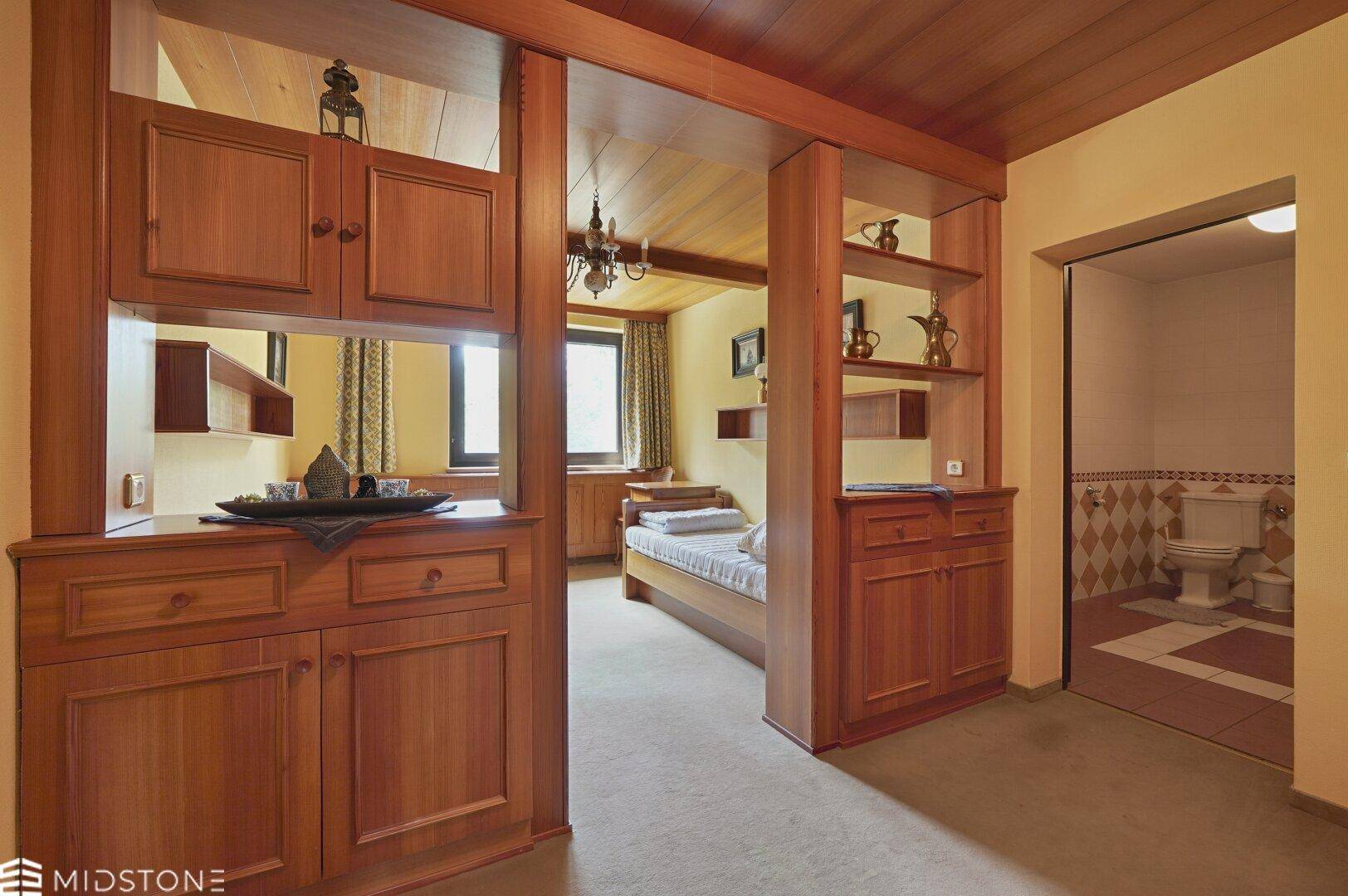 Schlafzimmer mit integrierten Holzmöbeln und direktem Zugang zu einem Badezimmer.