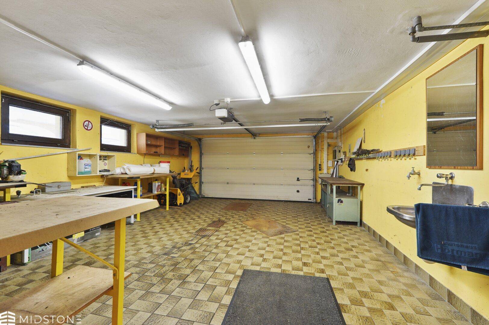 Geräumige Garage, die auch als Werkstatt dient, mit gelben Wänden und gefliestem Boden.