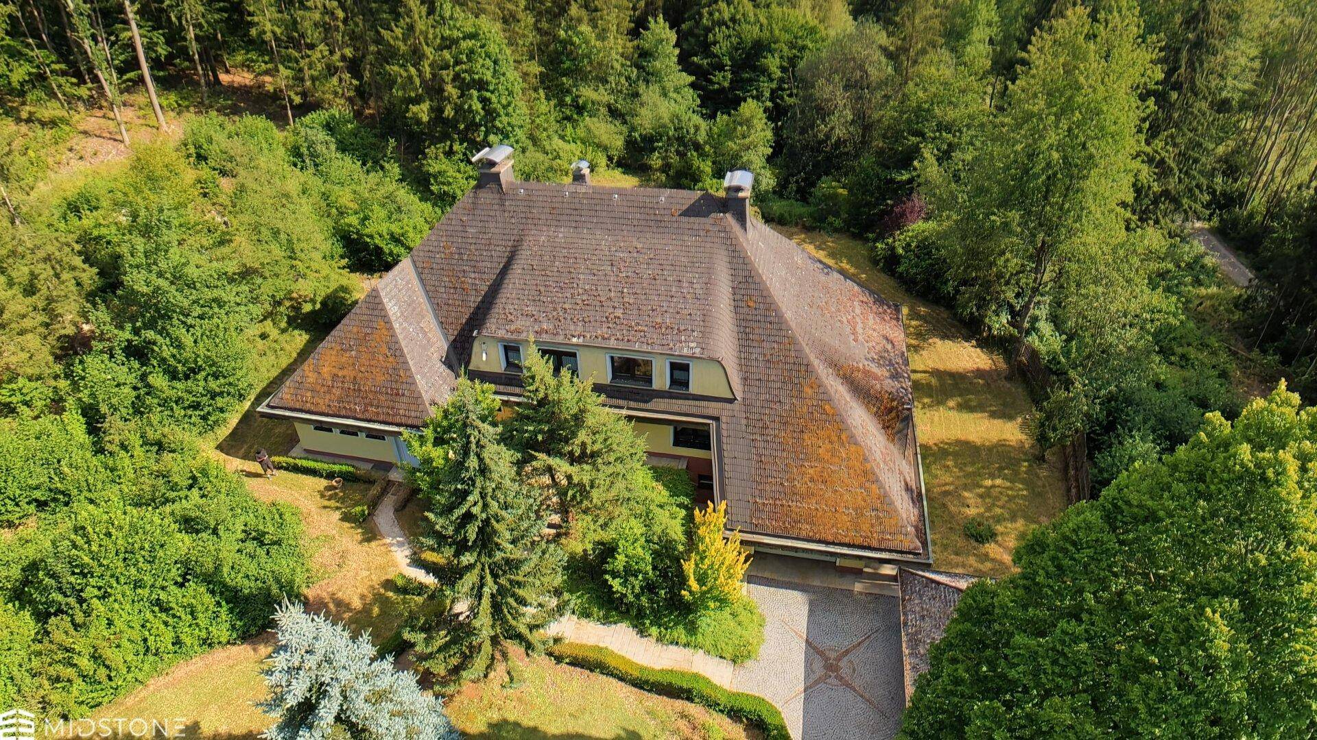 Vogelperspektive des Anwesens, umgeben von dichtem Wald und gepflegten Grünflächen.