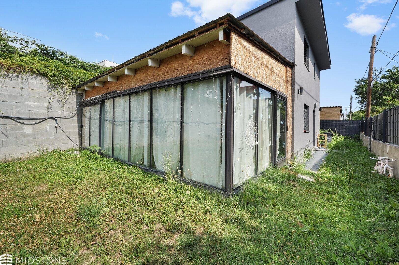 Hinterhof mit Wintergarten und Rasenfläche neben dem Gebäude.