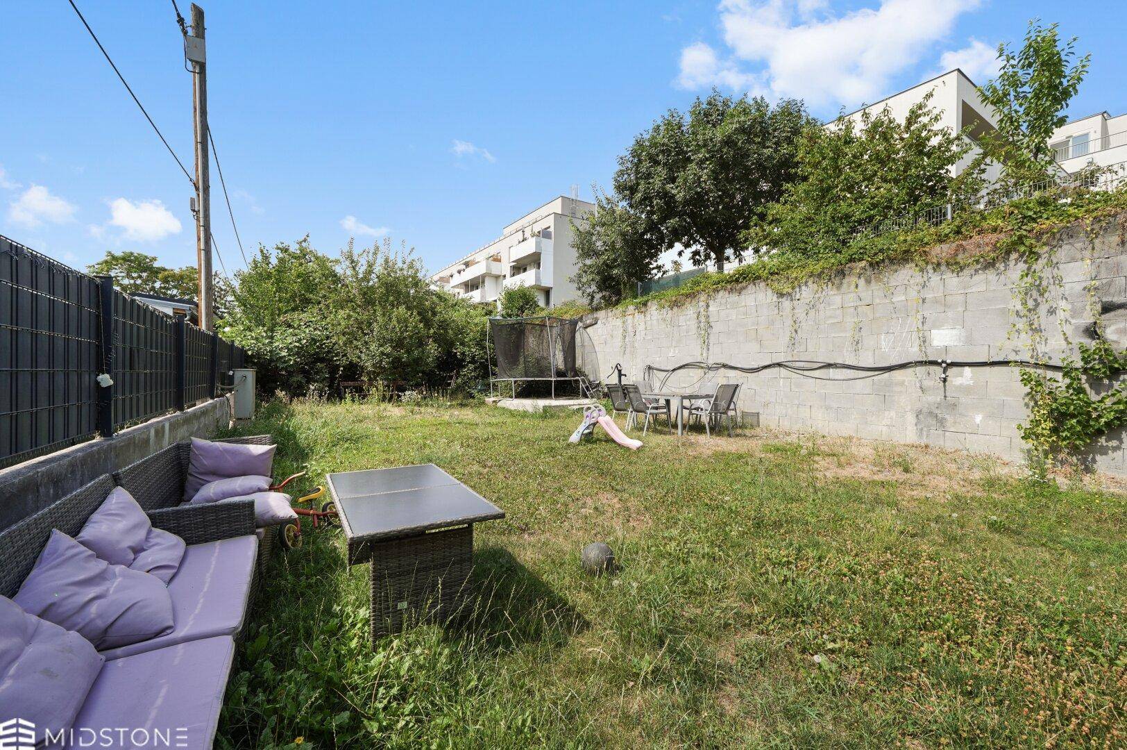 Großer Gartenbereich mit Rasenfläche, Sitzgelegenheiten und Trampolin.
