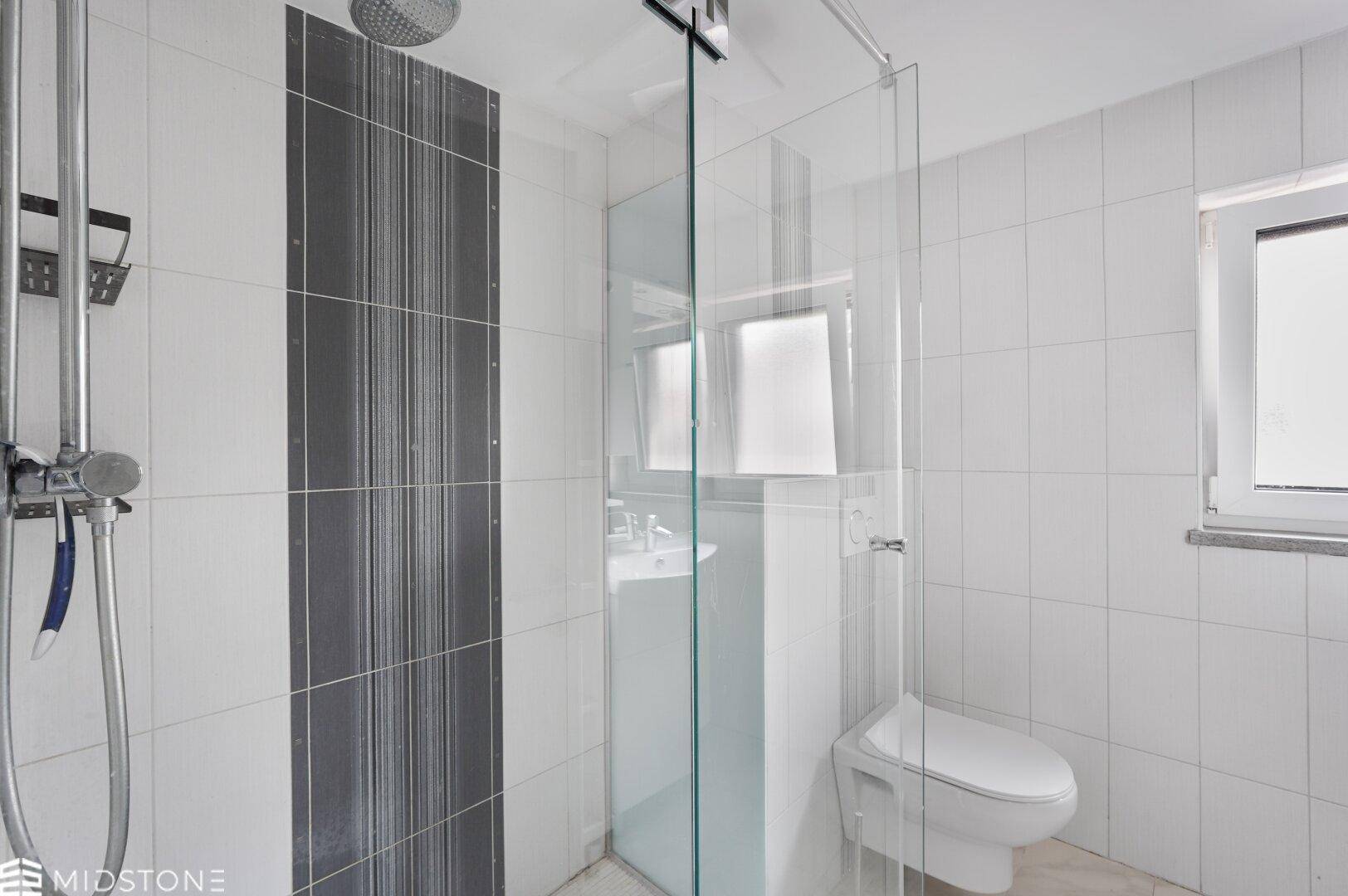 Modernes Badezimmer mit Duschkabine, Wand-WC und weißen Fliesen.
