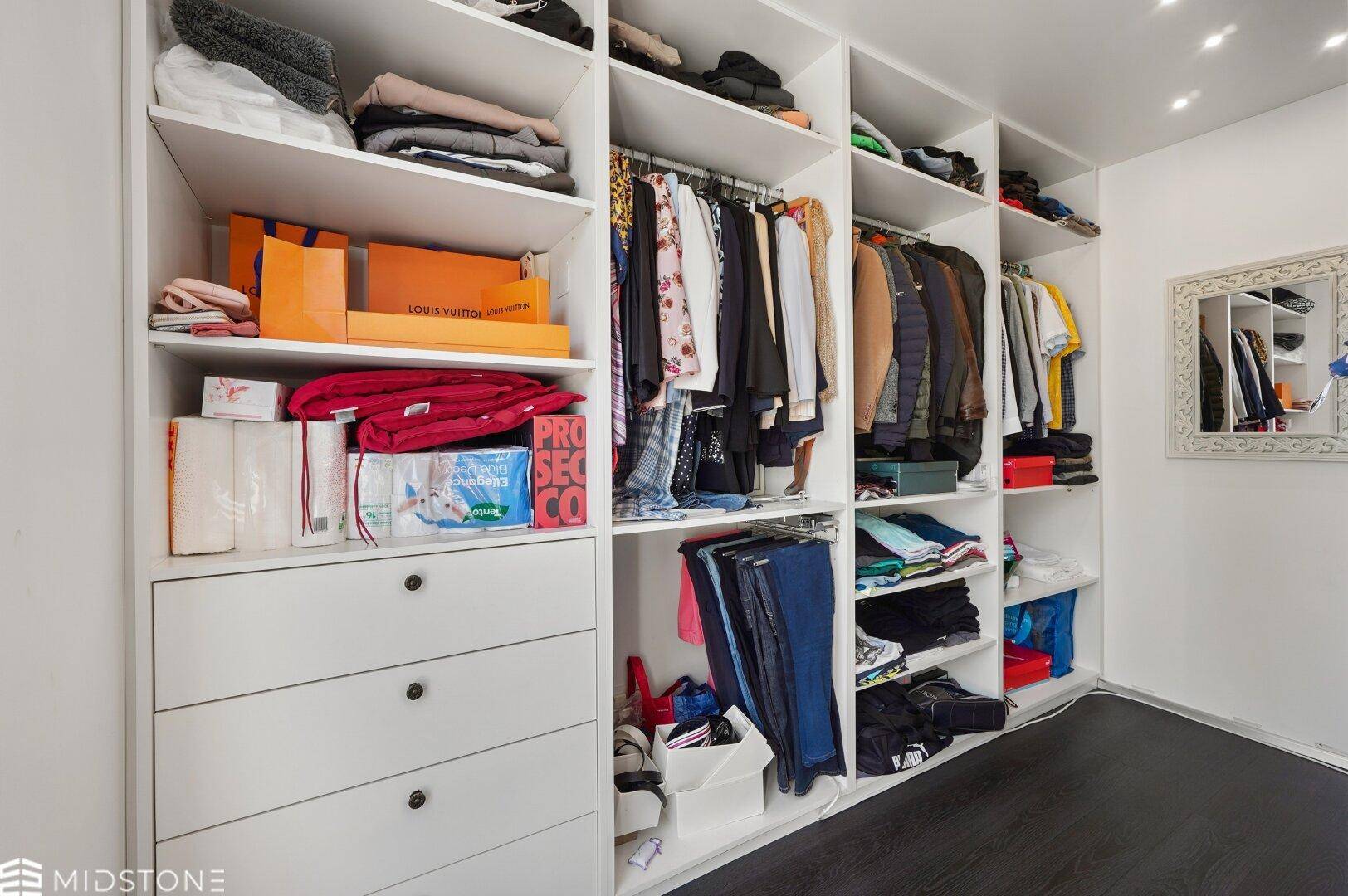Geräumiger begehbarer Kleiderschrank mit vielen Regalen und Stauraum.