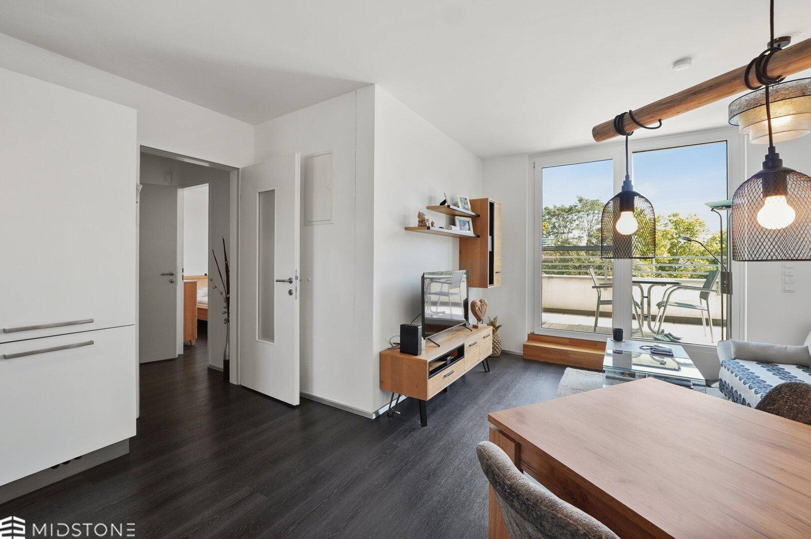 Wohnbereich mit dunklem Holzboden, TV-Möbel und Blick in den Flur.