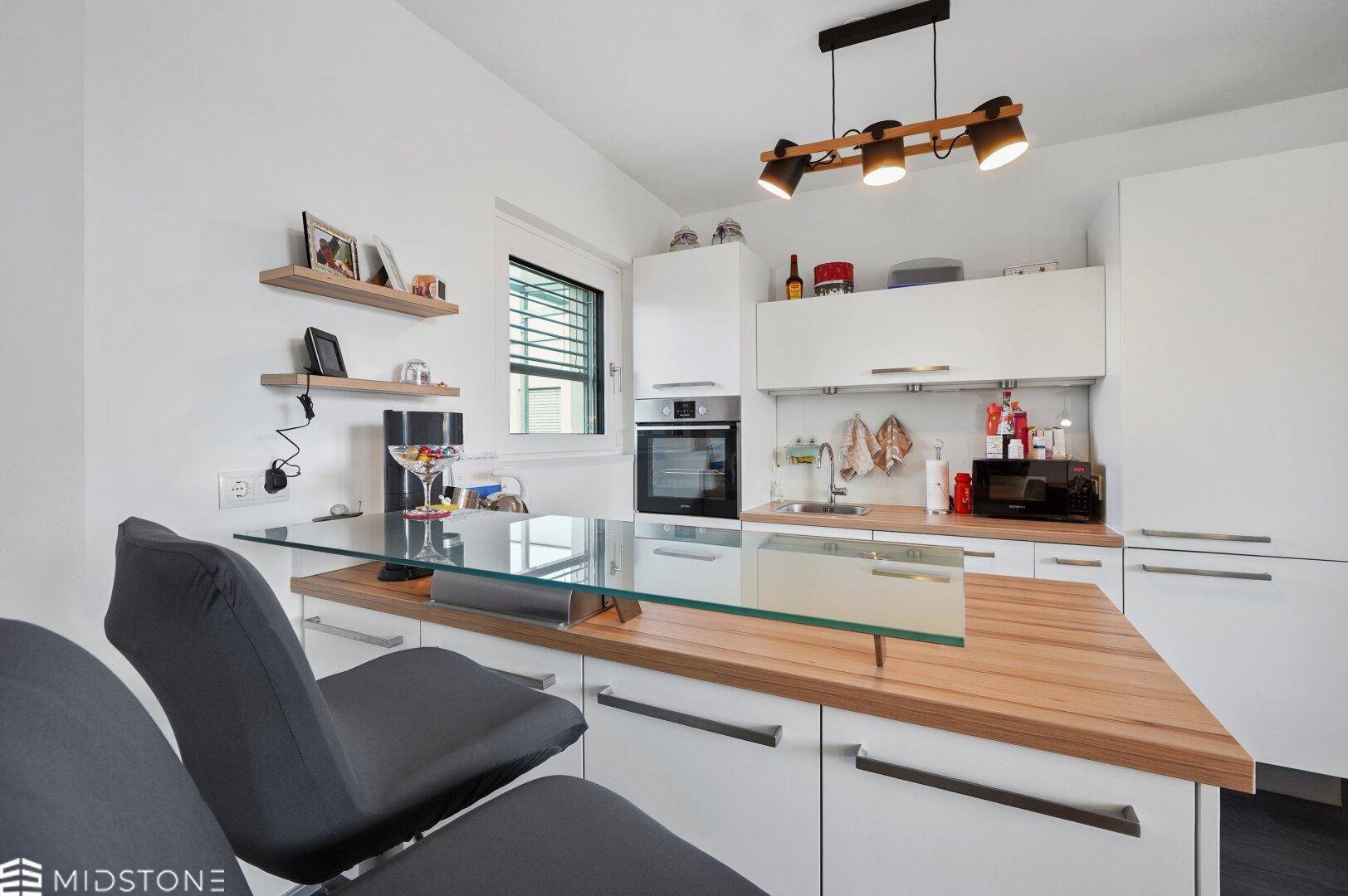 Detailansicht der modernen Kücheninsel mit Frühstücksbar und Kochfeld.