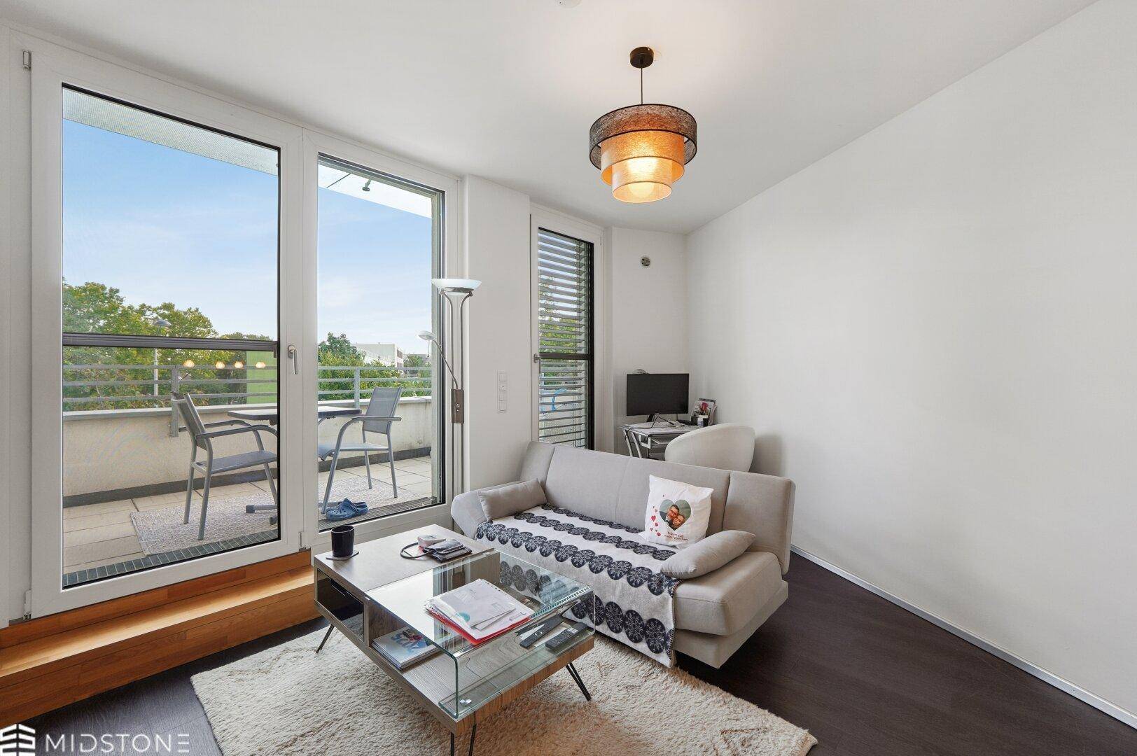 Gemütliches Wohnzimmer mit Sofa, Couchtisch und direktem Zugang zum Balkon.