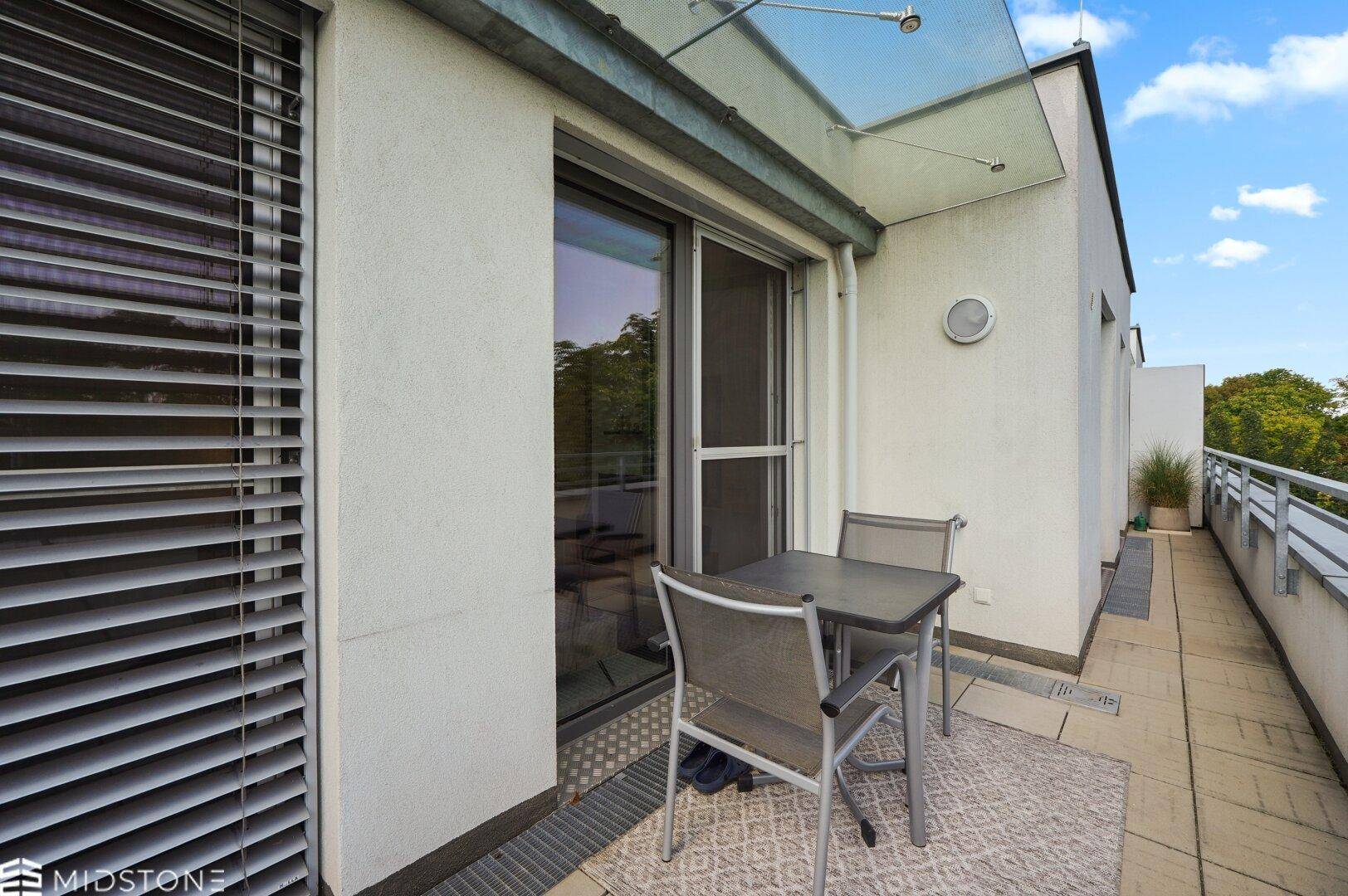Schmaler Balkon mit Sitzgelegenheiten und Blick auf die Umgebung.