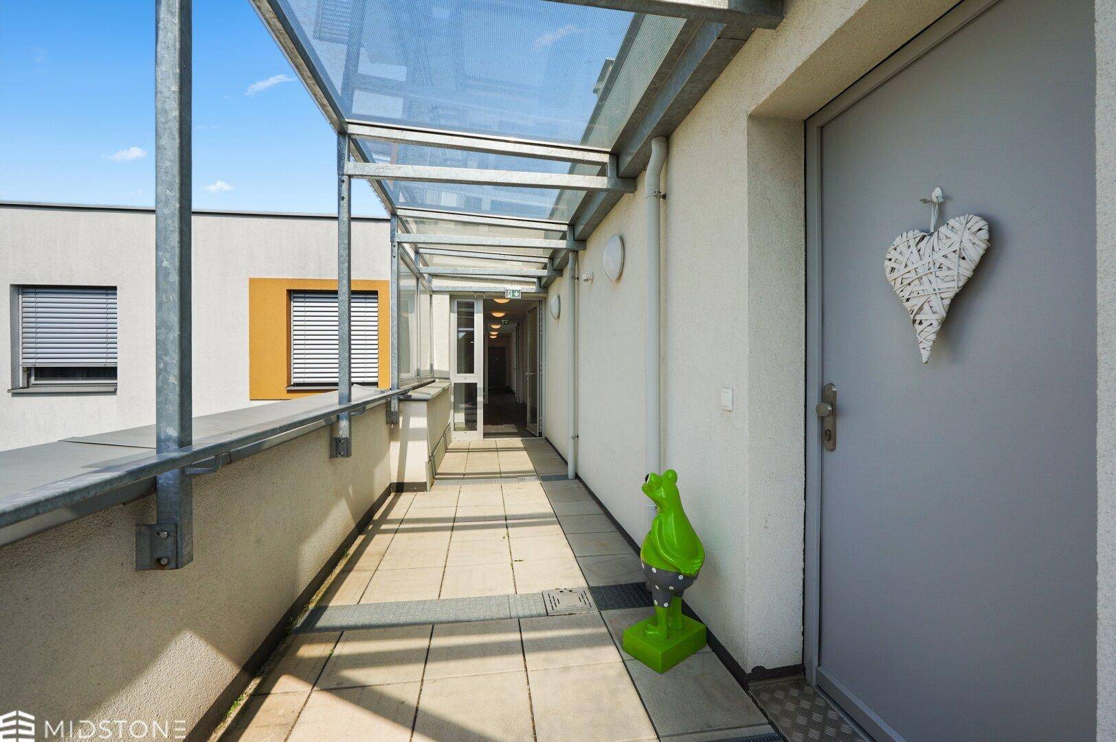 Überdachter Außenbalkon, der zu den verschiedenen Wohneinheiten führt.
