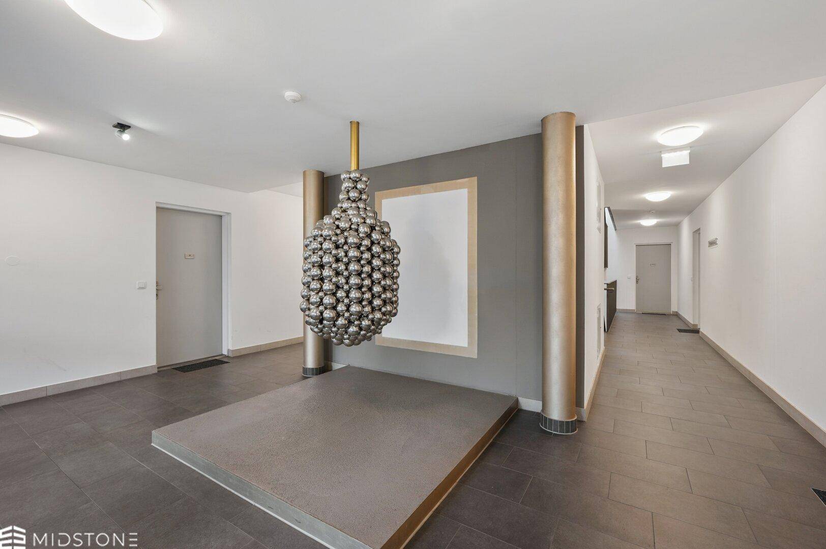 Moderner Eingangsbereich mit dekorativer Skulptur und Fliesenboden.