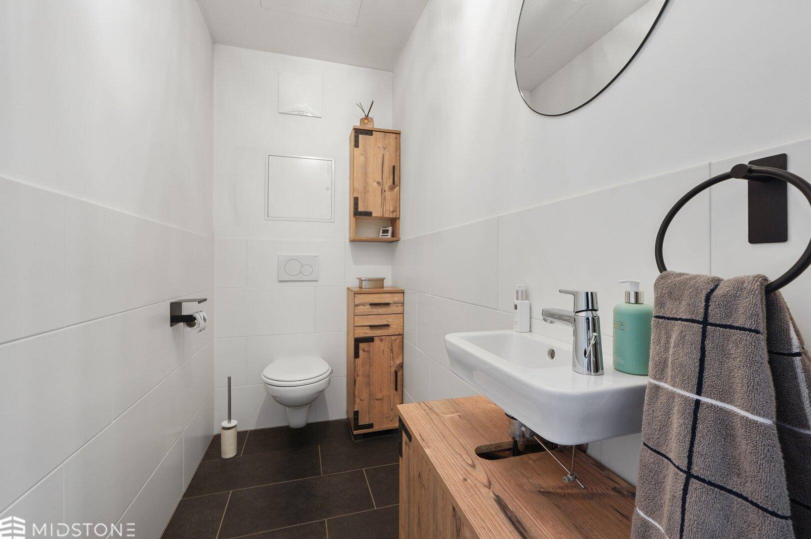 Modernes Gäste-WC mit Waschbecken, Wand-WC und Holzakzenten.