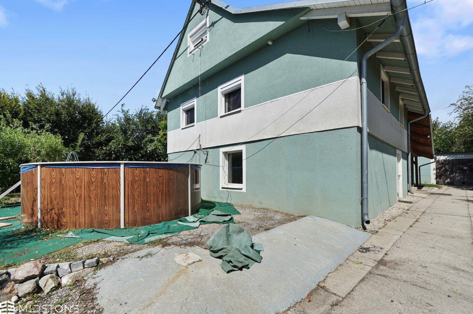 Seitenansicht des Hauses mit oberirdischem Pool und Zugang zum Gartenbereich.