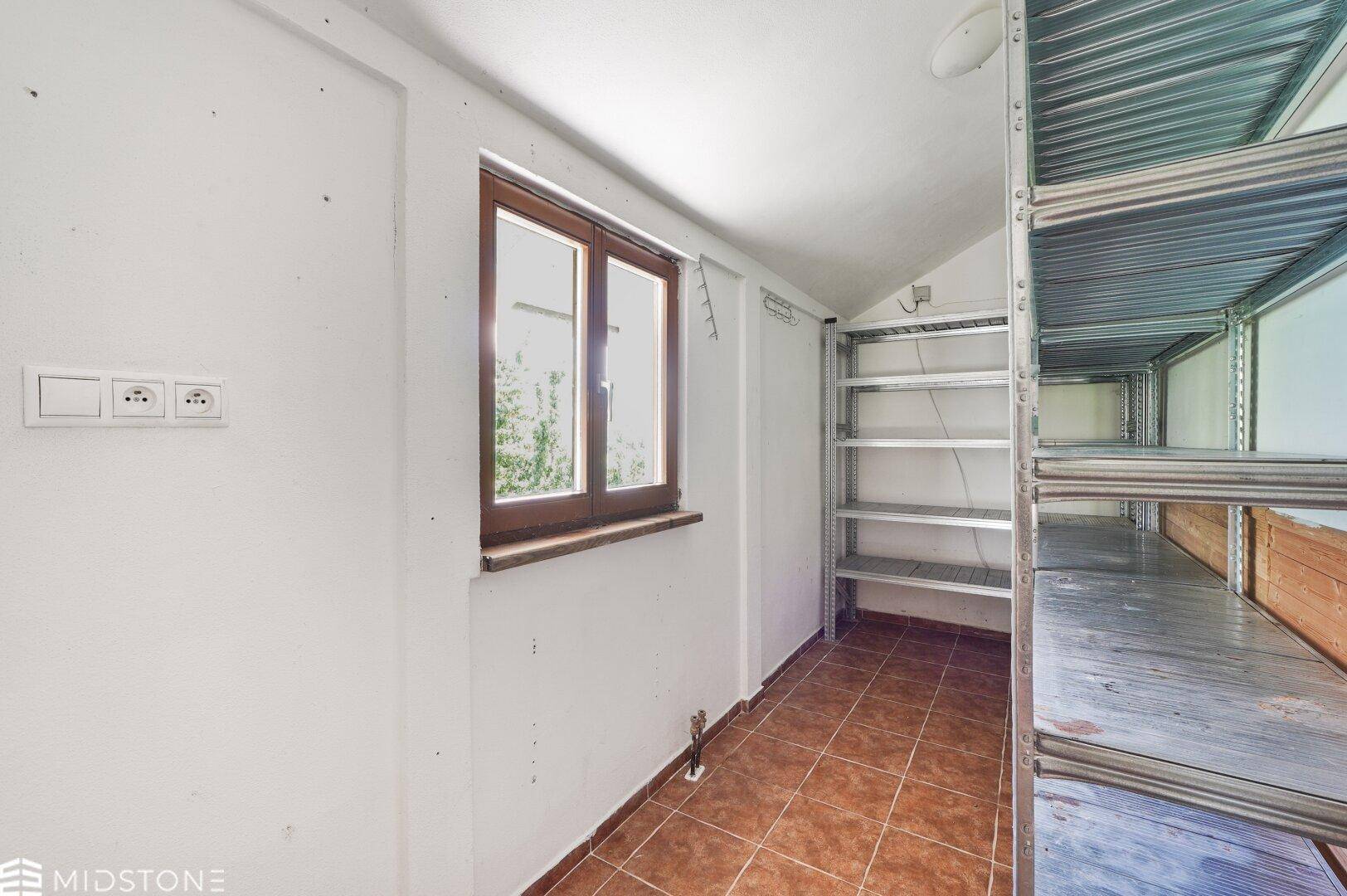 Abstellraum mit Fenster und Metallregalen für Lagerzwecke und Stauraum.