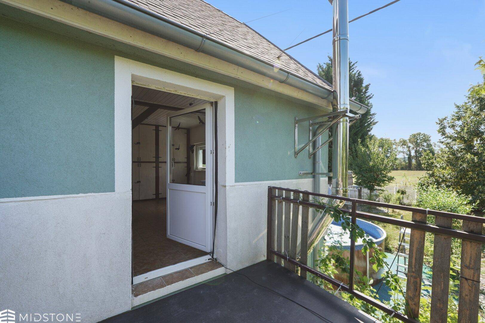 Kleiner Balkon mit Holzbalkon und Blick auf die grüne Umgebung und Natur.