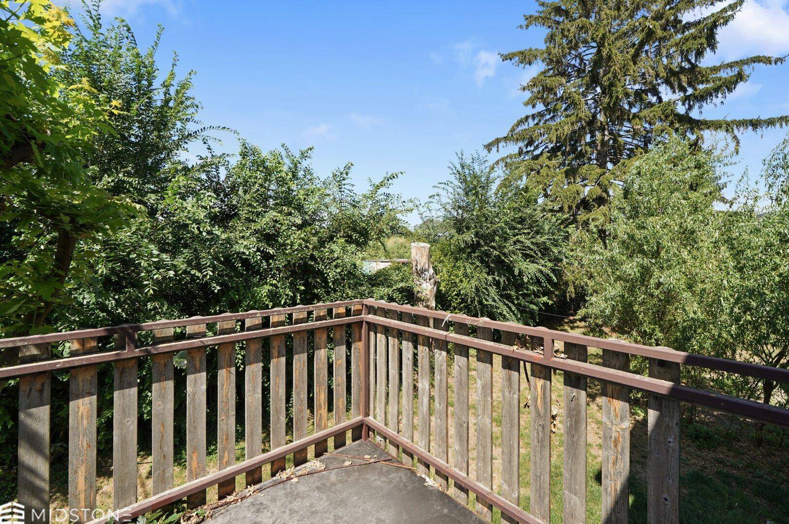Balkon mit Holzbalkon und Panoramablick auf die umliegende Natur und Bäume.