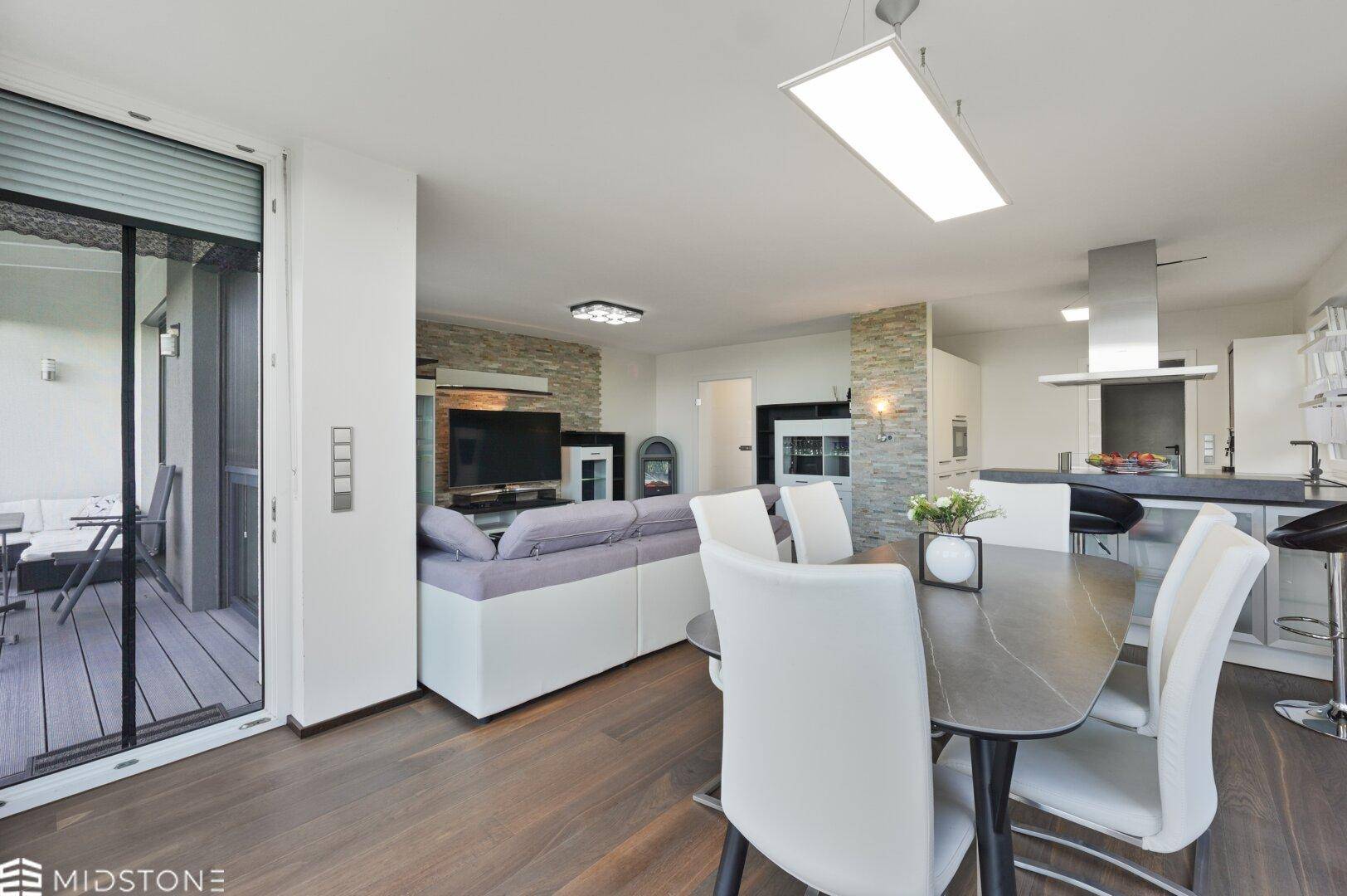 Heller Essbereich mit modernem Tisch und Stühlen, angrenzend an Wohnzimmer und Küche mit Terrassenzugang.