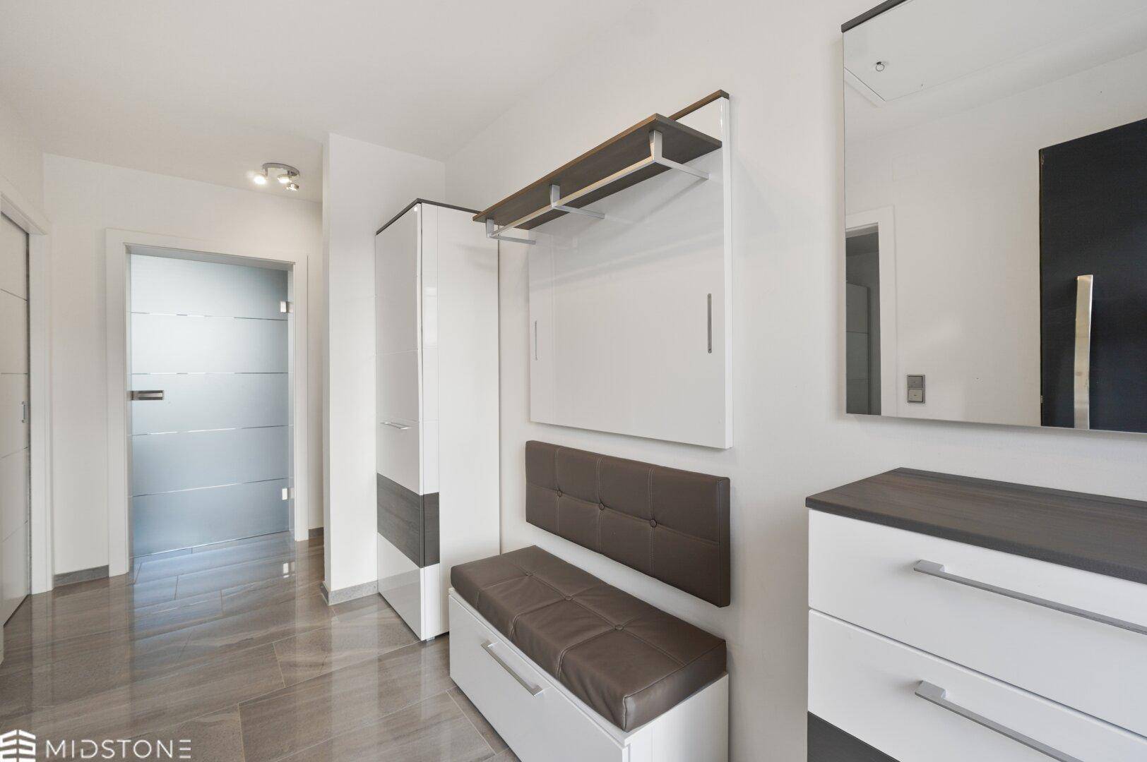 Modern eingerichteter Flur mit Garderobe, Sitzbank und Spiegel.