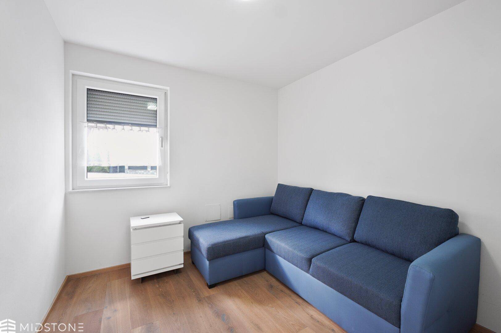 Gemütliches Zimmer mit blauem Ecksofa und Holzfußboden.