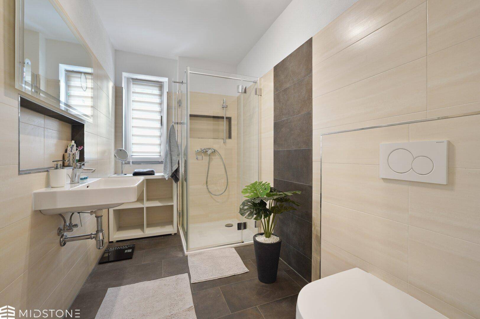 Modernes Badezimmer mit ebenerdiger Dusche, WC und hellem Fliesenboden.