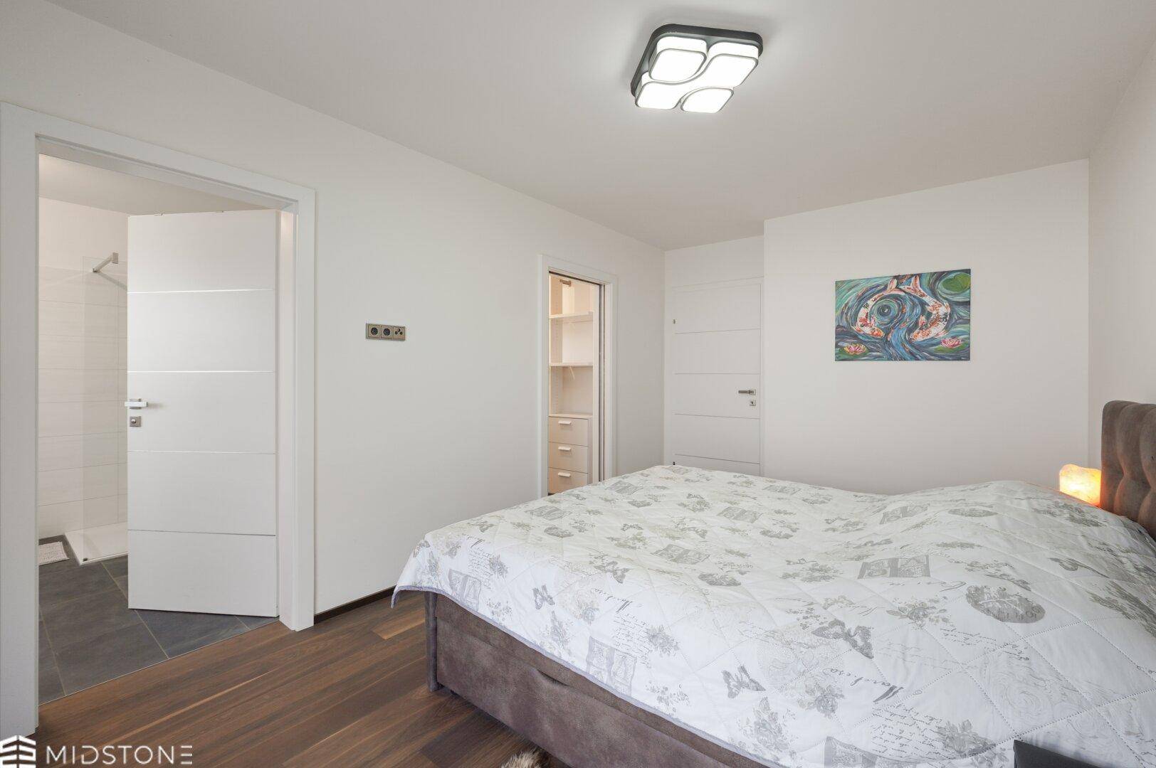 Schlafzimmer mit Zugang zu einem Badezimmer und einem begehbaren Kleiderschrank.
