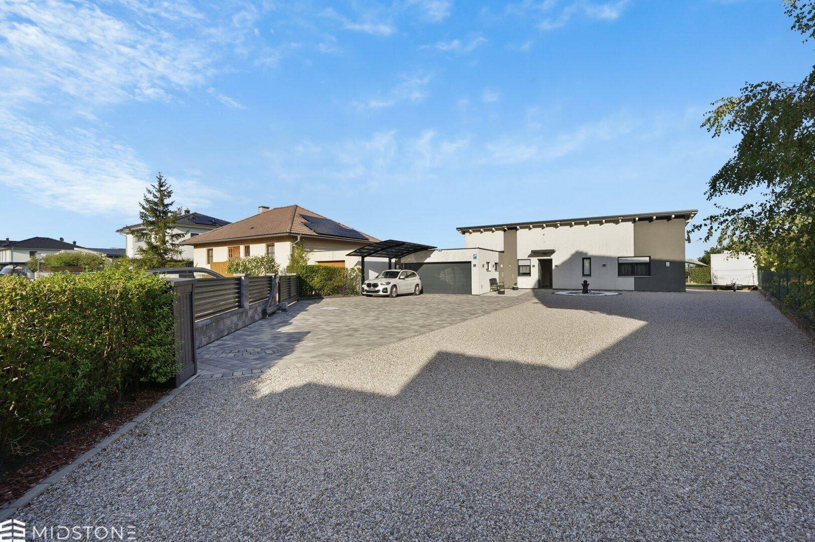 Modernes Einfamilienhaus mit großem Kies-Vorgarten und Carport.
