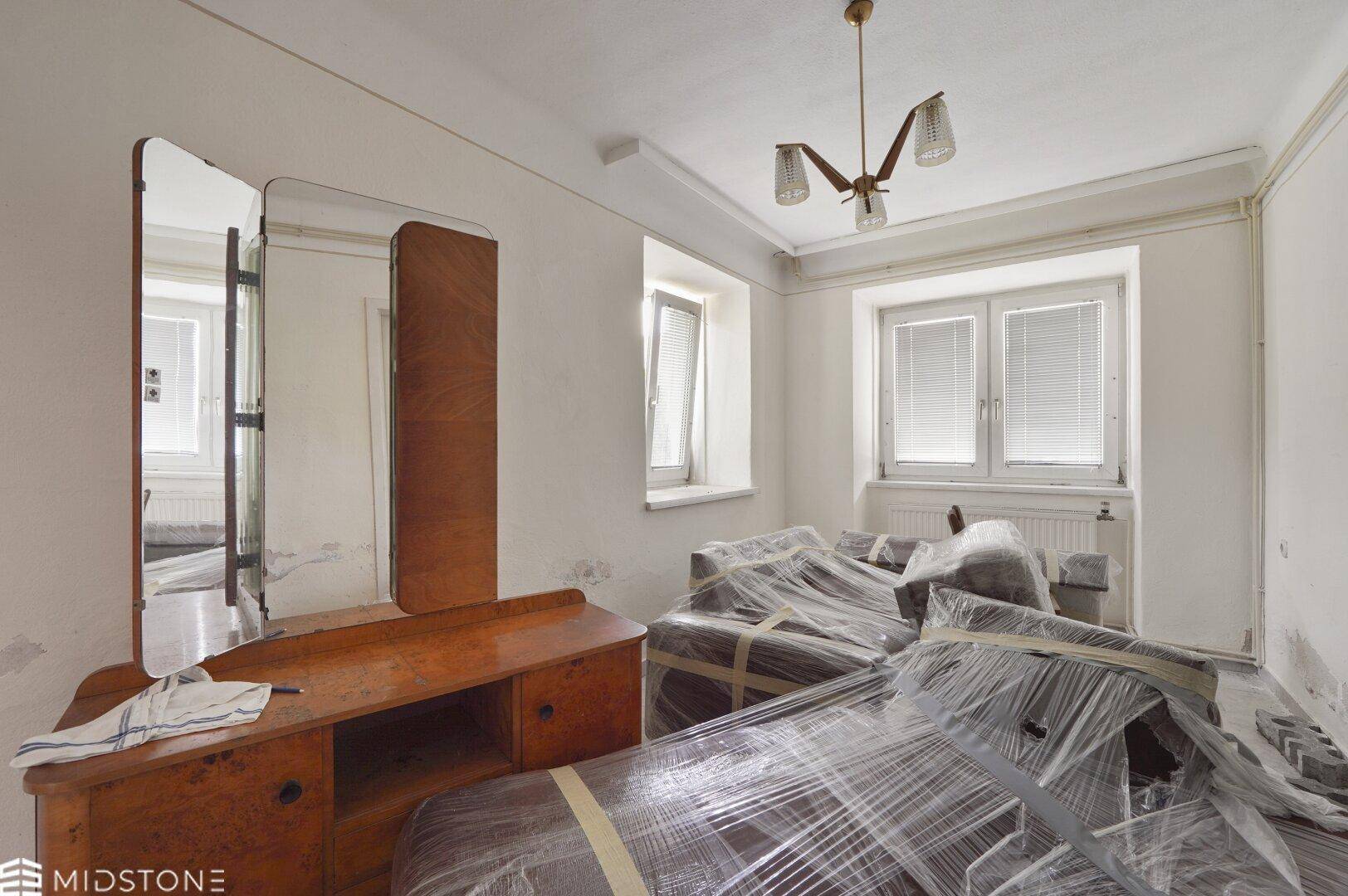 Schlafzimmer mit verpackten Möbeln und einem Vintage-Schminktisch, bereit für den Umzug oder die Renovierung.