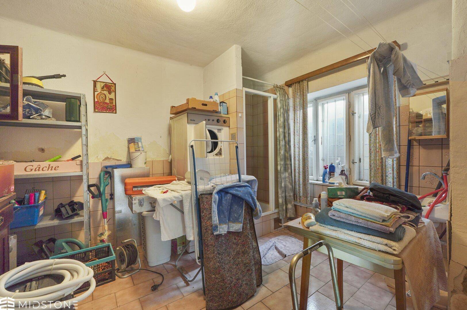 Praktischer Hauswirtschaftsraum mit Waschmaschine, Dusche und Fenster, ideal für den täglichen Gebrauch.