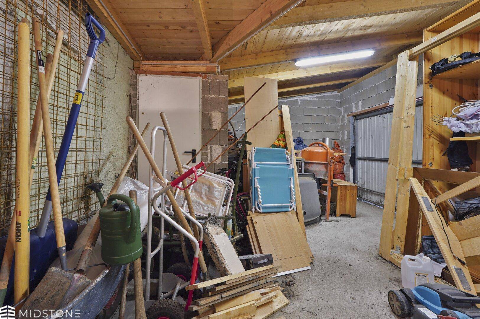 Geräumige Garage oder Abstellraum mit Werkzeugen, Baumaterialien und Holzdecke.