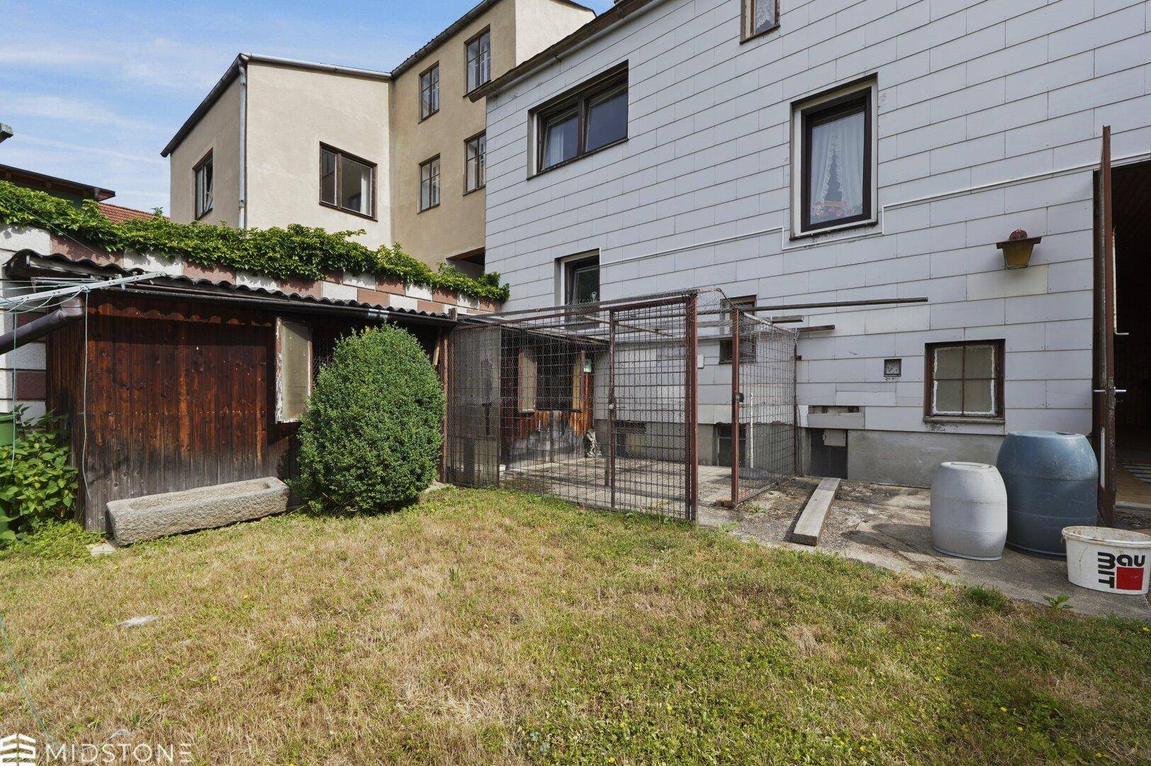 Gartenbereich mit Rasen, einem kleinen Schuppen und der Rückseite des Hauses.