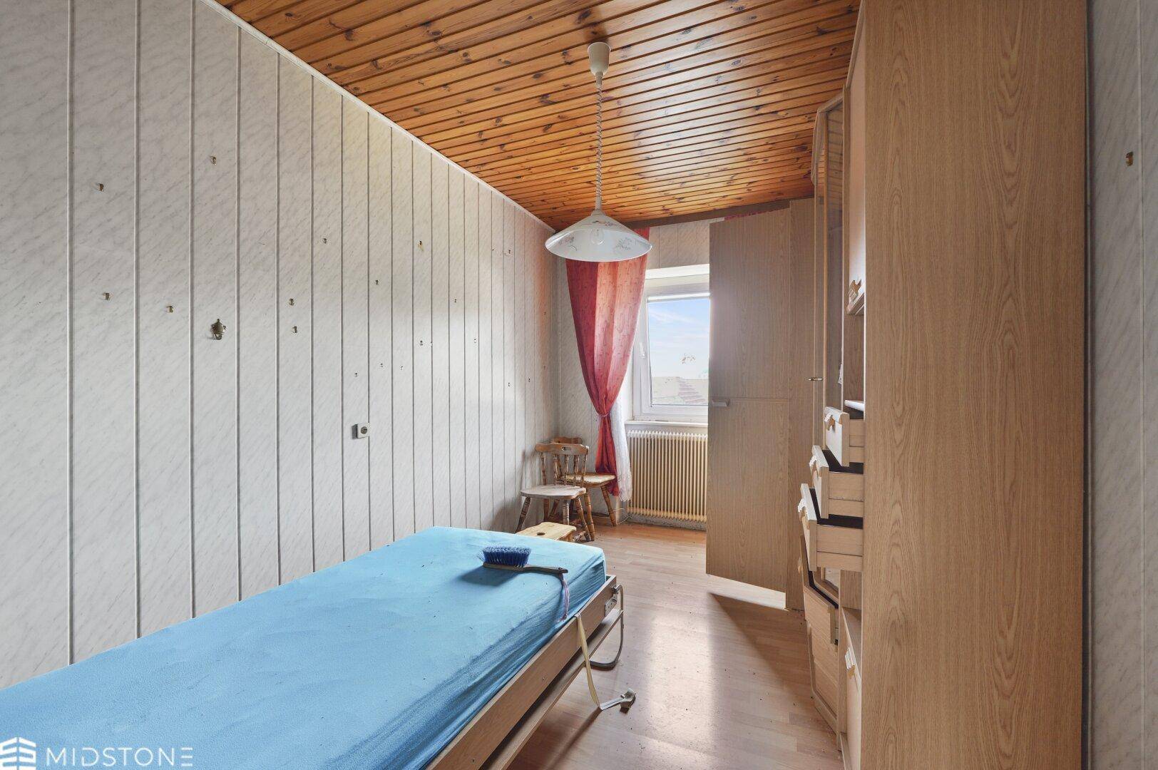 Schlafzimmer mit Holzdecke, weißer Wandvertäfelung und einem Einzelbett.